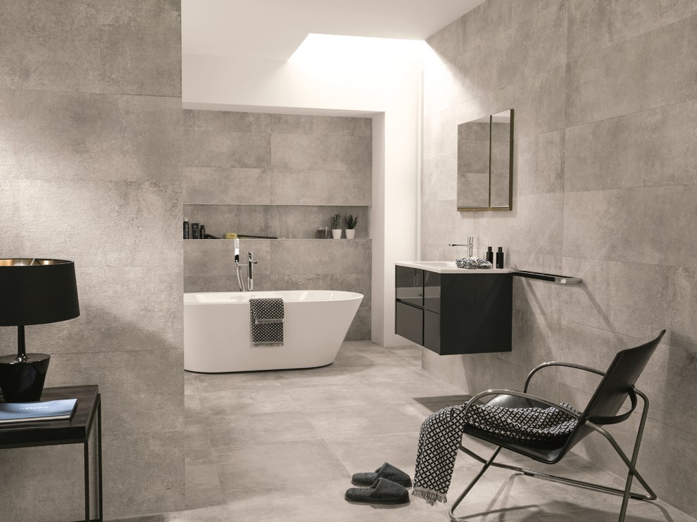 Exempel på ett modernt badrum, med släta luckor, svarta skåp, ett fristående badkar, grå kakel, keramikplattor, grå väggar, klinkergolv i porslin, ett integrerad handfat och bänkskiva i akrylsten