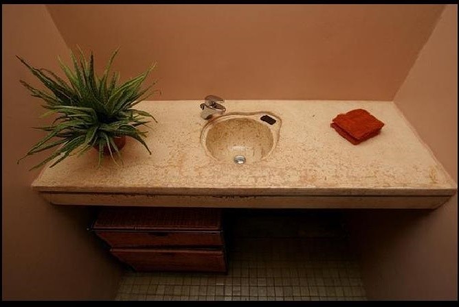 Modern inredning av ett litet badrum med dusch, med ett integrerad handfat, öppna hyllor, bänkskiva i betong, en dusch i en alkov, en toalettstol med separat cisternkåpa, brun kakel, glaskakel, beige väggar och mosaikgolv