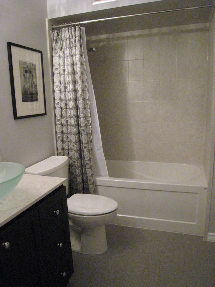 Modelo de cuarto de baño minimalista pequeño con lavabo sobreencimera, armarios estilo shaker, puertas de armario negras, encimera de cuarzo compacto, combinación de ducha y bañera y baldosas y/o azulejos grises