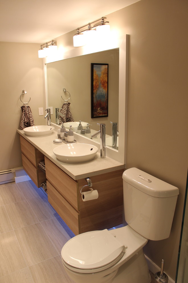 Cette photo montre une salle de bain chic en bois clair avec une vasque, un placard à porte plane, un plan de toilette en quartz modifié, une baignoire en alcôve, un combiné douche/baignoire, WC séparés, un carrelage beige et des carreaux de porcelaine.