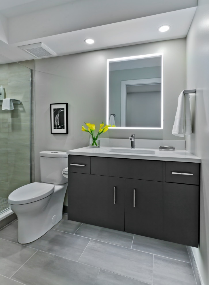 This is an example of a medium sized contemporary shower room bathroom in Minneapolis with flat-panel cabinets, grey cabinets, an alcove shower, a two-piece toilet, grey tiles, ceramic tiles, grey walls, ceramic flooring, a submerged sink, engineered stone worktops, a hinged door and white worktops.