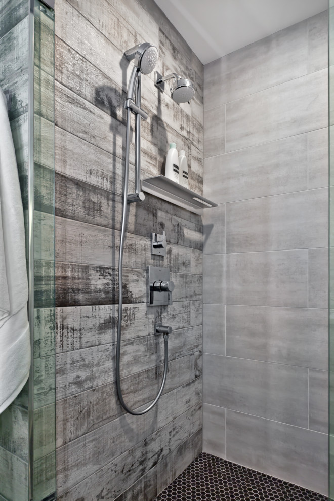 Small trendy 3/4 gray tile and ceramic tile ceramic tile and gray floor corner shower photo in Minneapolis with flat-panel cabinets, black cabinets, a two-piece toilet, white walls, an undermount sink, solid surface countertops, a hinged shower door and white countertops