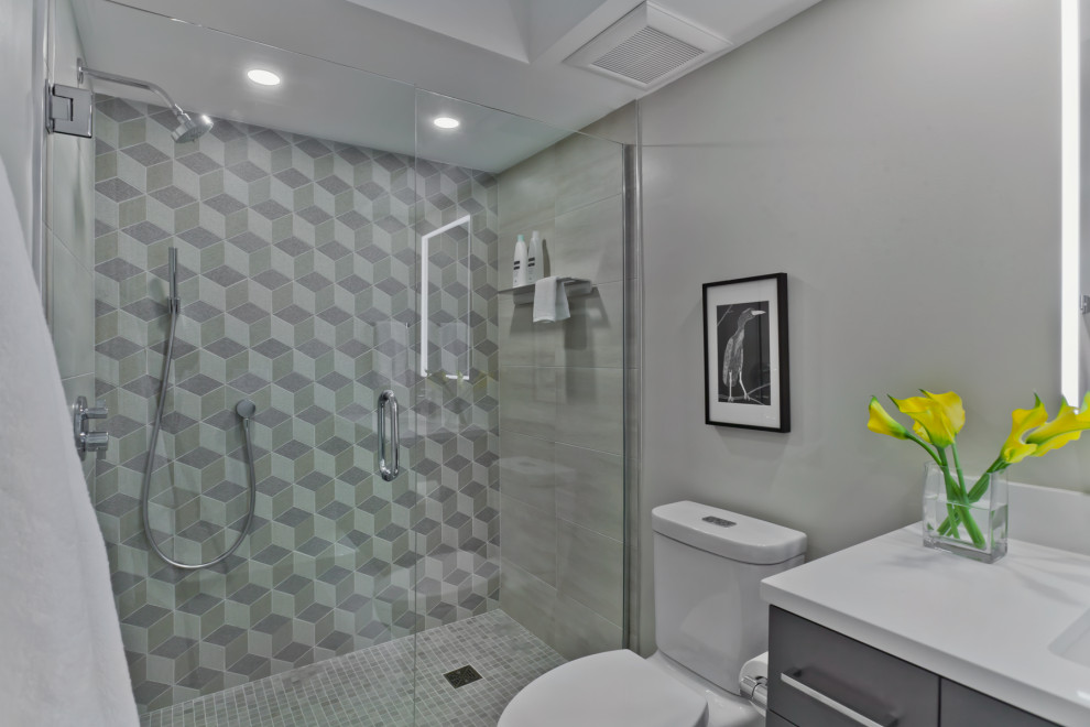Идея дизайна: ванная комната среднего размера в современном стиле с плоскими фасадами, серыми фасадами, душем в нише, раздельным унитазом, серой плиткой, керамической плиткой, серыми стенами, полом из керамической плитки, душевой кабиной, врезной раковиной, столешницей из искусственного кварца, душем с распашными дверями и белой столешницей