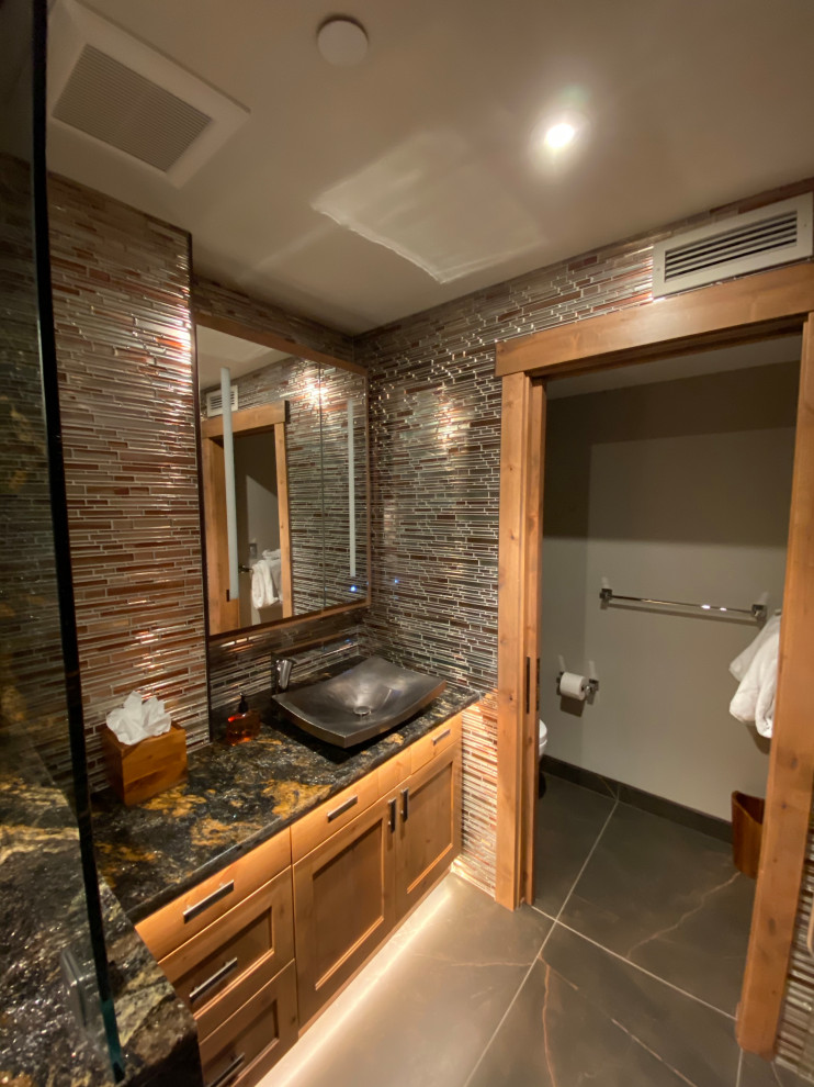 Пример оригинального дизайна: маленькая главная ванная комната в стиле рустика с фасадами в стиле шейкер, коричневыми фасадами, душем в нише, раздельным унитазом, оранжевой плиткой, стеклянной плиткой, бежевыми стенами, полом из керамогранита, накладной раковиной, столешницей из гранита, коричневым полом, душем с распашными дверями и разноцветной столешницей для на участке и в саду