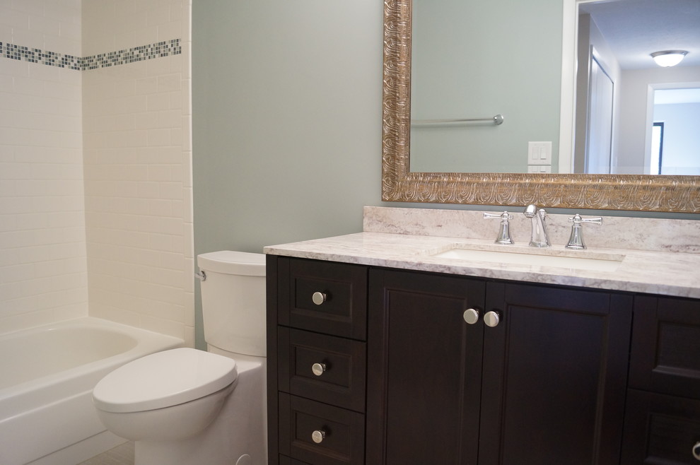 This is an example of a small modern bathroom in Cleveland with an integrated sink, shaker cabinets, dark wood cabinets, solid surface worktops, a built-in bath, a one-piece toilet, white tiles, ceramic tiles, blue walls and porcelain flooring.