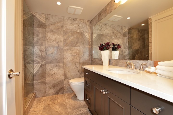 Foto på ett litet funkis badrum med dusch, med skåp i shakerstil, svarta skåp, en dusch i en alkov, beige kakel, stenkakel, ett undermonterad handfat, bänkskiva i akrylsten, en toalettstol med separat cisternkåpa, beige väggar och klinkergolv i porslin