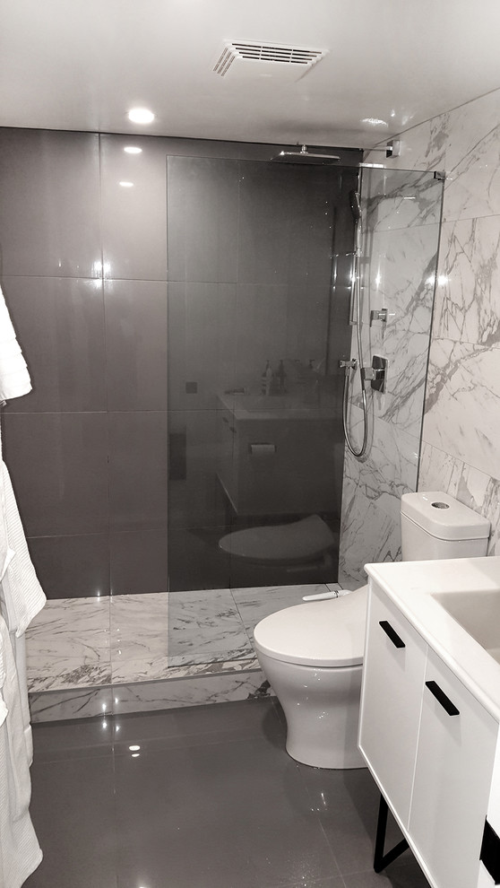 Пример оригинального дизайна: ванная комната среднего размера в стиле модернизм с фасадами островного типа, белыми фасадами, душем в нише, унитазом-моноблоком, серой плиткой, керамогранитной плиткой, разноцветными стенами, полом из керамогранита, душевой кабиной, монолитной раковиной, столешницей из искусственного камня, серым полом и открытым душем