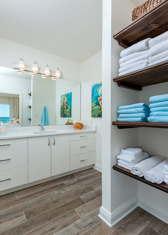 Mid-sized beach style 3/4 medium tone wood floor and brown floor bathroom photo in Other with flat-panel cabinets, white cabinets, white walls, an undermount sink and solid surface countertops