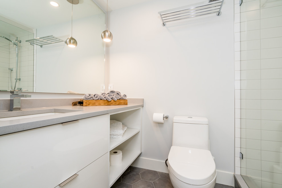 На фото: маленькая детская ванная комната в современном стиле с плоскими фасадами, белыми фасадами, душем в нише, унитазом-моноблоком, белой плиткой, керамогранитной плиткой, белыми стенами, полом из керамогранита, врезной раковиной, столешницей из искусственного кварца, серым полом, душем с распашными дверями и серой столешницей для на участке и в саду