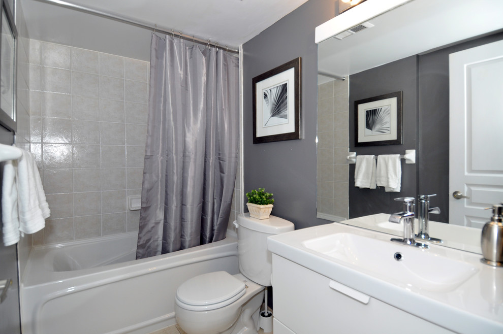 Inspiration för moderna badrum, med släta luckor, vita skåp, ett badkar i en alkov, en dusch/badkar-kombination, en toalettstol med separat cisternkåpa, grå väggar och ett integrerad handfat