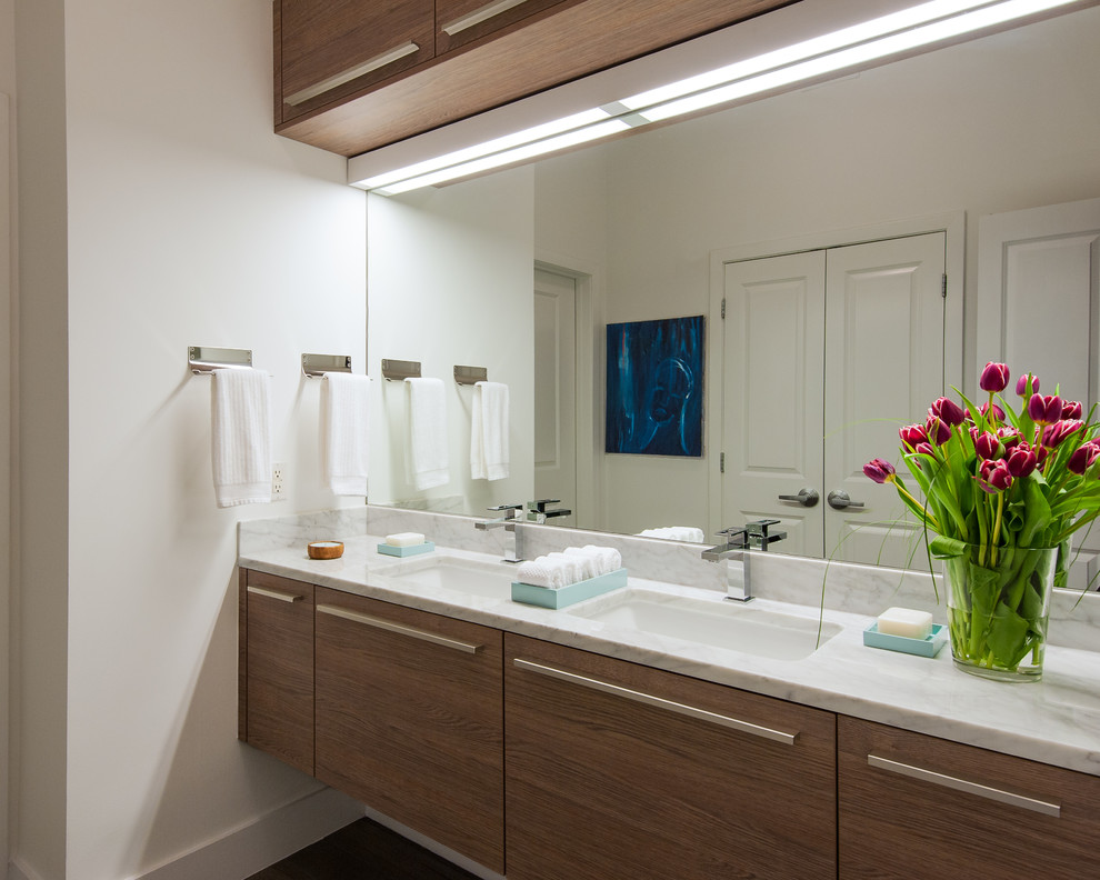 Esempio di una stanza da bagno minimal di medie dimensioni con lavabo sottopiano, ante lisce, ante in legno scuro e pareti bianche