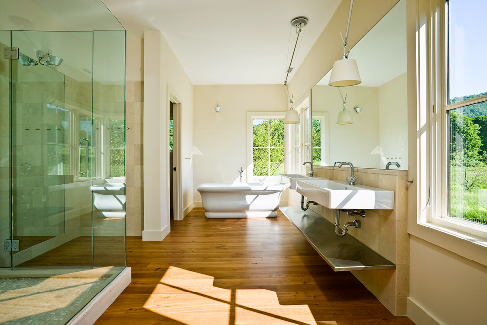 Exemple d'une très grande salle de bain principale nature avec un lavabo suspendu, un placard sans porte, une baignoire indépendante, une douche d'angle, un carrelage beige, un carrelage de pierre, un mur beige, un sol en bois brun, WC à poser, un sol marron et une cabine de douche à porte battante.