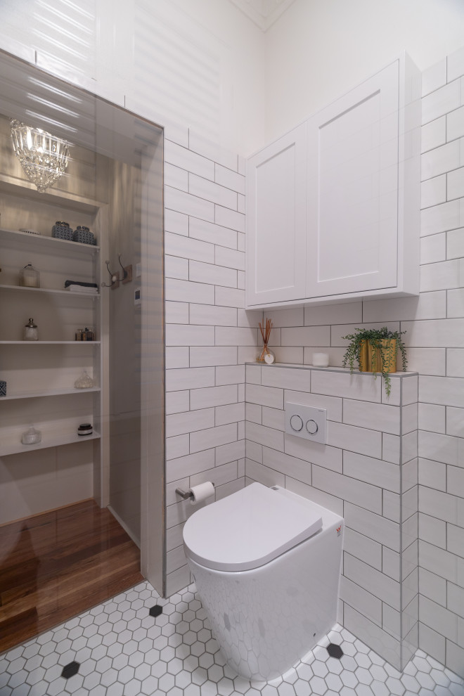 Immagine di una piccola stanza da bagno con doccia contemporanea con WC monopezzo, piastrelle bianche, piastrelle in gres porcellanato, pareti bianche, pavimento in gres porcellanato, pavimento bianco e nicchia