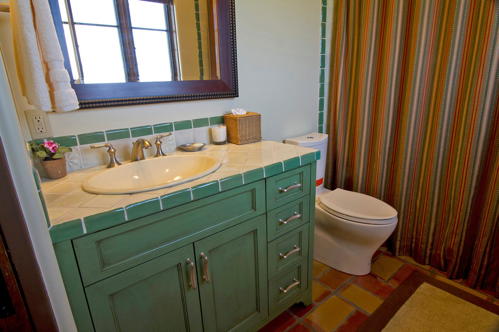 Amerikansk inredning av ett mellanstort badrum, med skåp i shakerstil, skåp i slitet trä, kaklad bänkskiva, ett badkar i en alkov, en dusch/badkar-kombination, en toalettstol med separat cisternkåpa, beige kakel, beige väggar och klinkergolv i terrakotta