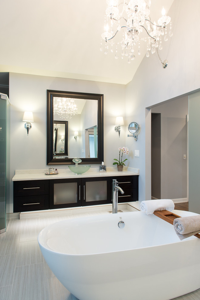 Inspiration for a large contemporary ensuite bathroom in Detroit with glass-front cabinets, dark wood cabinets, a freestanding bath, a double shower, a bidet, grey tiles, pebble tiles, grey walls, porcelain flooring, a vessel sink and engineered stone worktops.