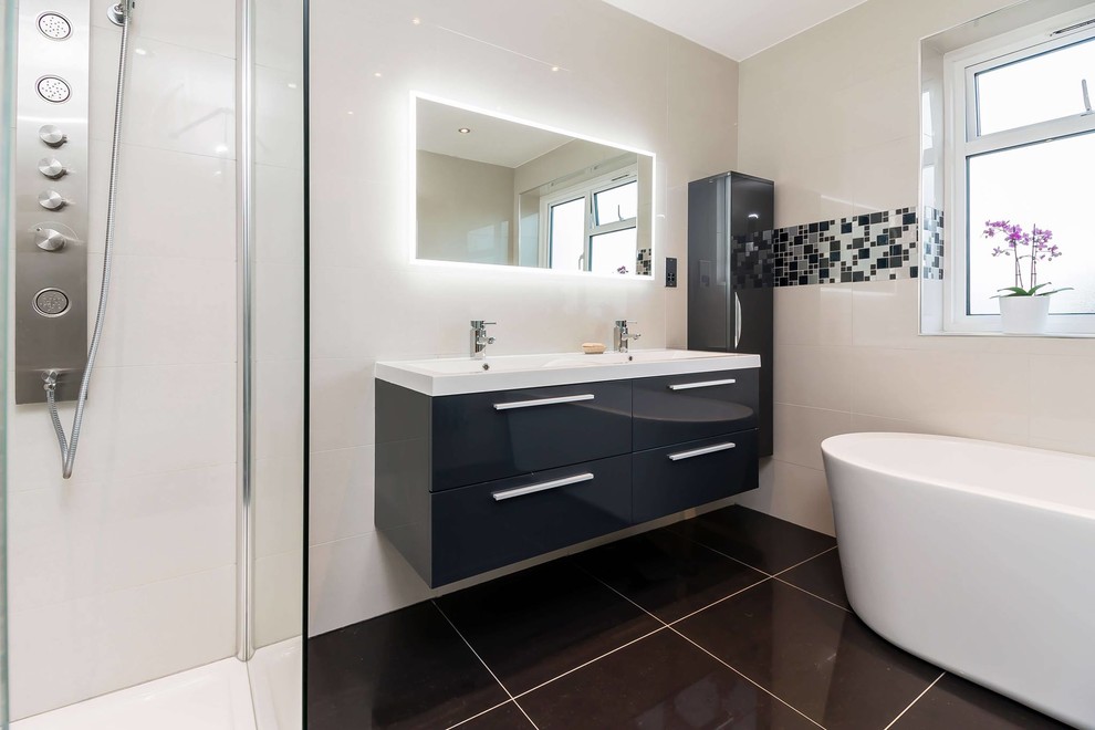 This is an example of a medium sized contemporary family bathroom in London with raised-panel cabinets, grey cabinets, a freestanding bath, a walk-in shower, a wall mounted toilet, black tiles, porcelain tiles, beige walls, porcelain flooring and a wall-mounted sink.
