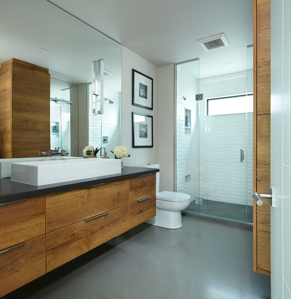 This is an example of a medium sized contemporary ensuite bathroom in Other with an alcove shower, a two-piece toilet, white tiles, porcelain tiles, white walls, concrete flooring, a vessel sink, engineered stone worktops, grey floors, a hinged door, flat-panel cabinets and medium wood cabinets.