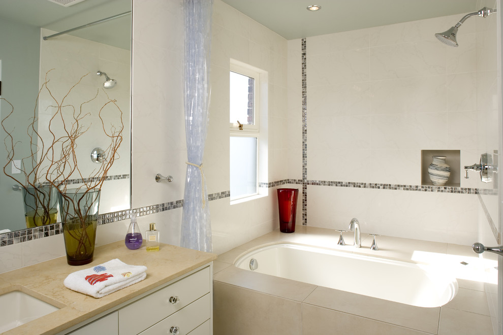 Immagine di una stanza da bagno mediterranea con lavabo sottopiano, ante lisce, ante bianche, vasca sottopiano, vasca/doccia e piastrelle bianche