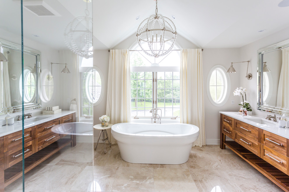 На фото: ванная комната в стиле неоклассика (современная классика) с врезной раковиной, фасадами цвета дерева среднего тона, отдельно стоящей ванной и белой плиткой