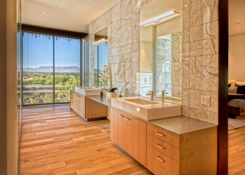 Diseño de cuarto de baño actual con armarios con paneles lisos, puertas de armario de madera oscura, suelo de madera en tonos medios, lavabo bajoencimera, suelo marrón y encimeras grises