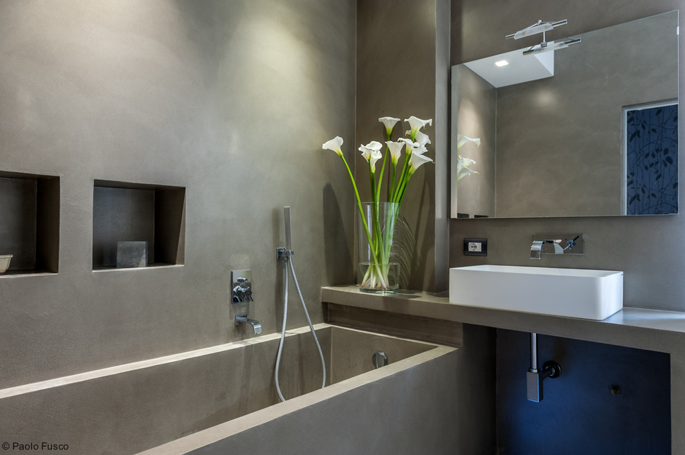 На фото: маленькая главная ванная комната в современном стиле с серыми фасадами, столешницей из бетона, угловой ванной, душем над ванной, раздельным унитазом, серой плиткой, серыми стенами и настольной раковиной для на участке и в саду