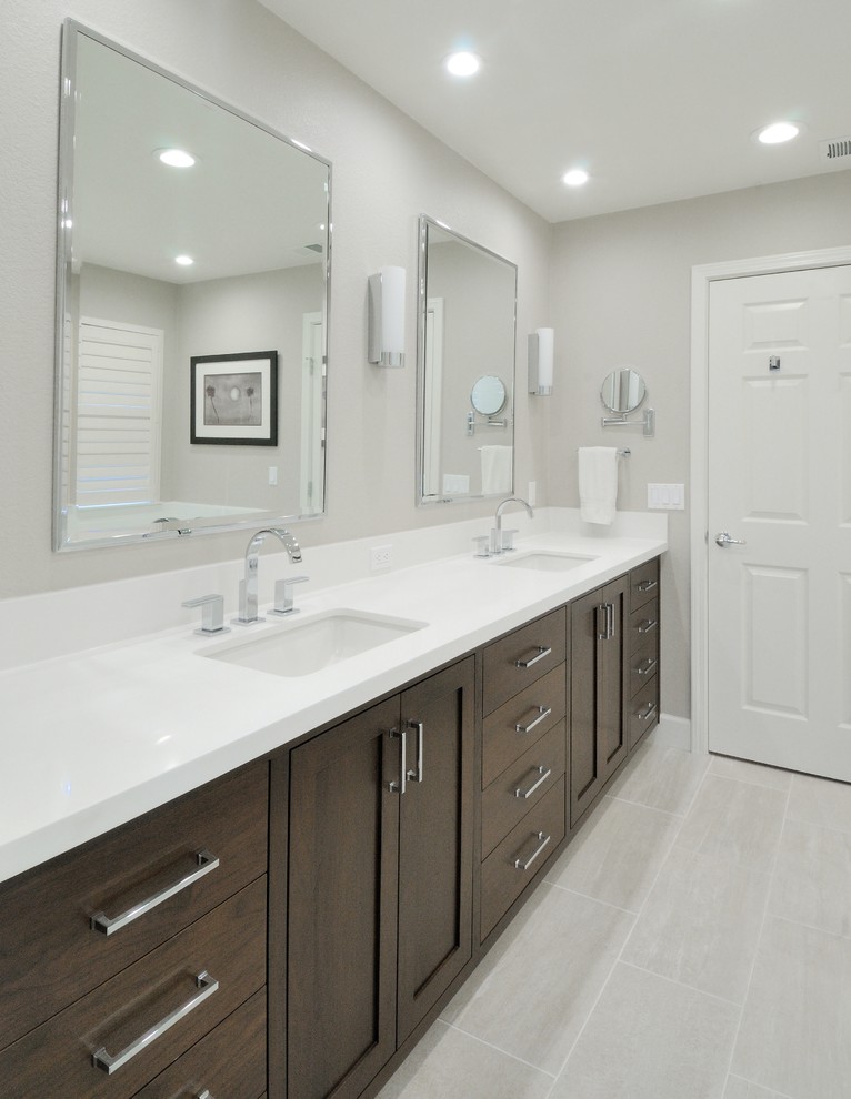 Exemple d'une salle de bain principale tendance en bois foncé de taille moyenne avec un lavabo encastré, un placard à porte shaker, un plan de toilette en surface solide, un carrelage gris, des carreaux de porcelaine, un mur gris et un sol en carrelage de porcelaine.