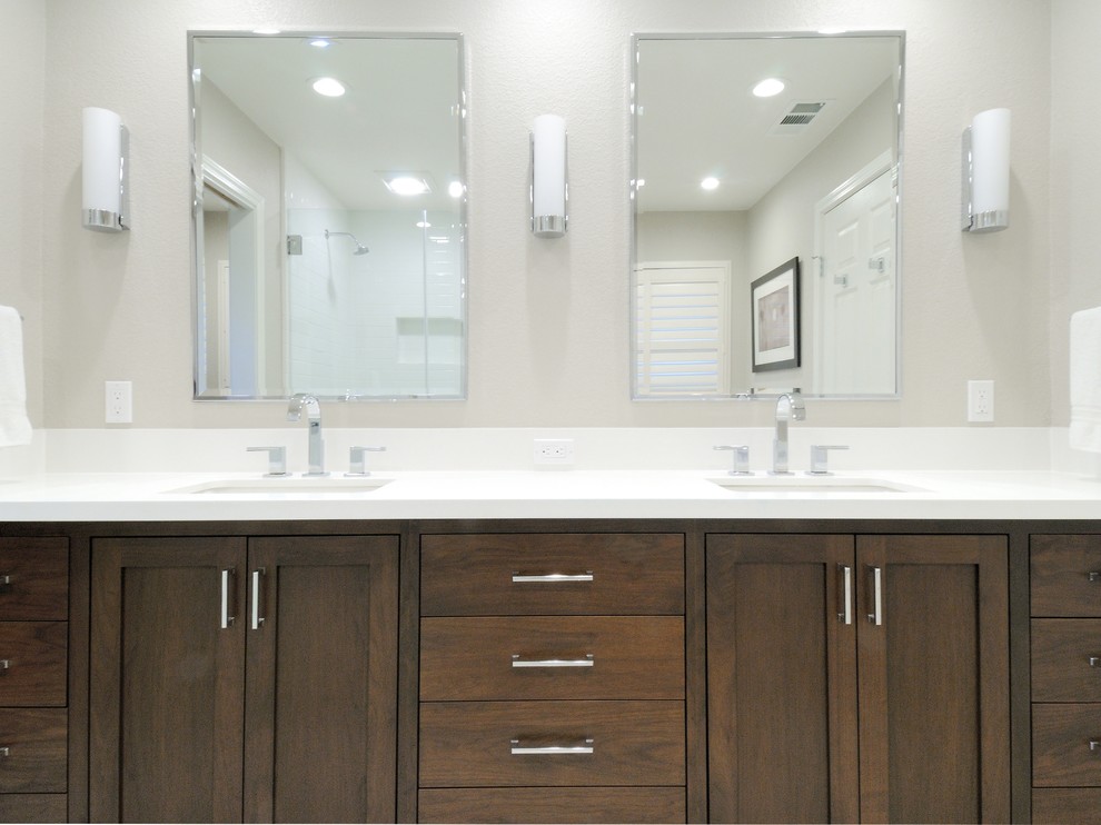 Cette photo montre une salle de bain principale tendance en bois foncé de taille moyenne avec un lavabo encastré, un placard à porte shaker, un plan de toilette en surface solide, un mur gris et un sol en carrelage de porcelaine.