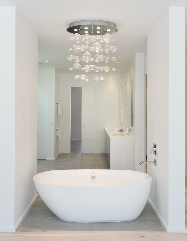 Пример оригинального дизайна: большая главная ванная комната в стиле модернизм с плоскими фасадами, столешницей из искусственного камня, отдельно стоящей ванной, белой плиткой, плиткой из листового стекла, серыми фасадами, открытым душем, унитазом-моноблоком, белыми стенами, полом из ламината, монолитной раковиной, бежевым полом и открытым душем