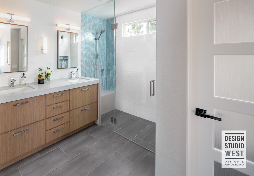 Design ideas for a medium sized contemporary ensuite bathroom in San Diego with flat-panel cabinets, grey cabinets, an alcove shower, multi-coloured tiles, glass tiles, white walls, porcelain flooring, a submerged sink, engineered stone worktops, grey floors, a hinged door and grey worktops.