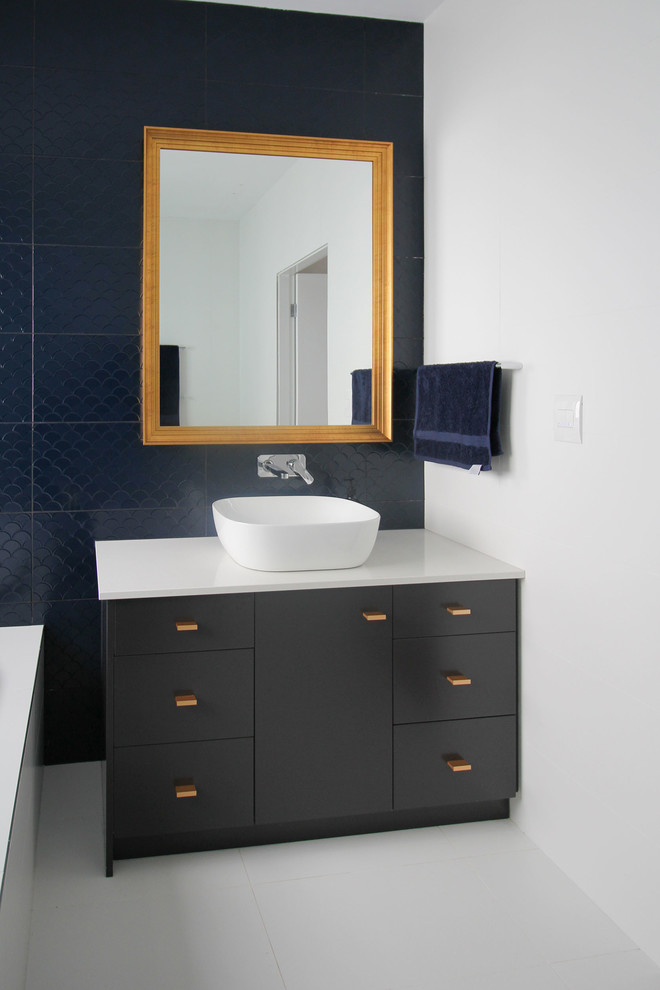Design ideas for a medium sized contemporary family bathroom in Sydney with flat-panel cabinets, black cabinets, a built-in bath, a corner shower, a one-piece toilet, blue tiles, porcelain tiles, white walls, porcelain flooring, a vessel sink, engineered stone worktops, white floors, a hinged door and white worktops.