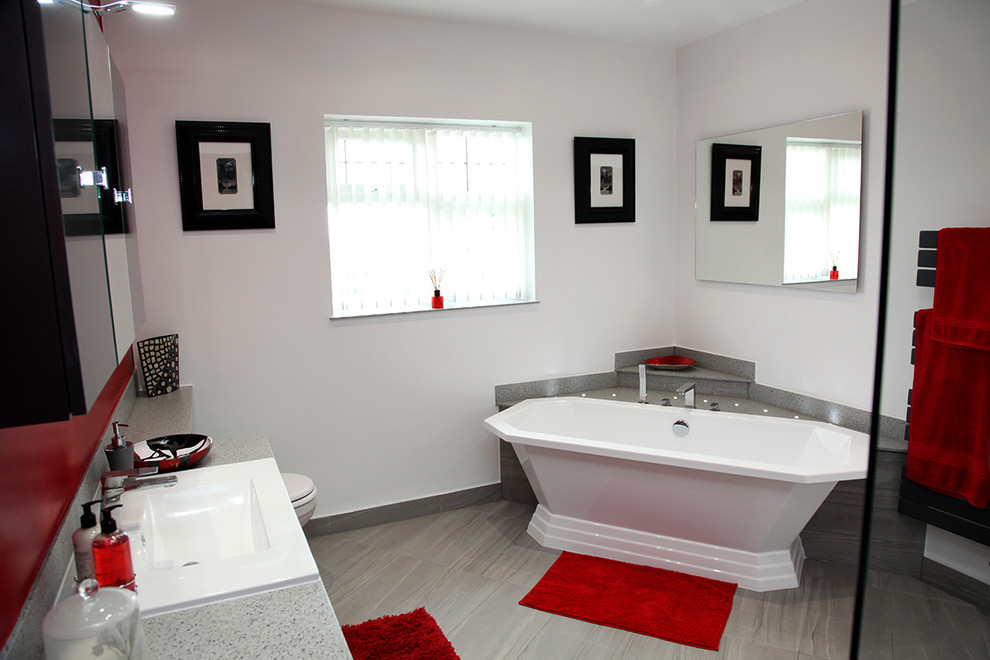 Свежая идея для дизайна: ванная комната среднего размера в современном стиле с плоскими фасадами, серыми фасадами, отдельно стоящей ванной, открытым душем, унитазом-моноблоком, красными стенами, душевой кабиной, настольной раковиной, столешницей из искусственного камня, серым полом, открытым душем и серой столешницей - отличное фото интерьера