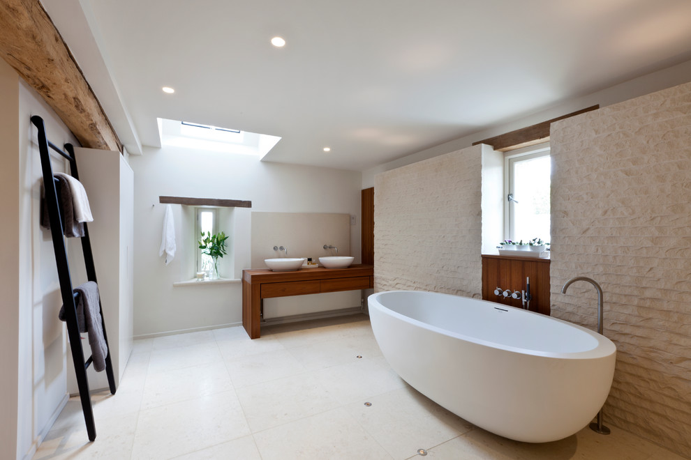 Inspiration for a contemporary master freestanding bathtub remodel in London with a vessel sink, flat-panel cabinets, dark wood cabinets, wood countertops and white walls