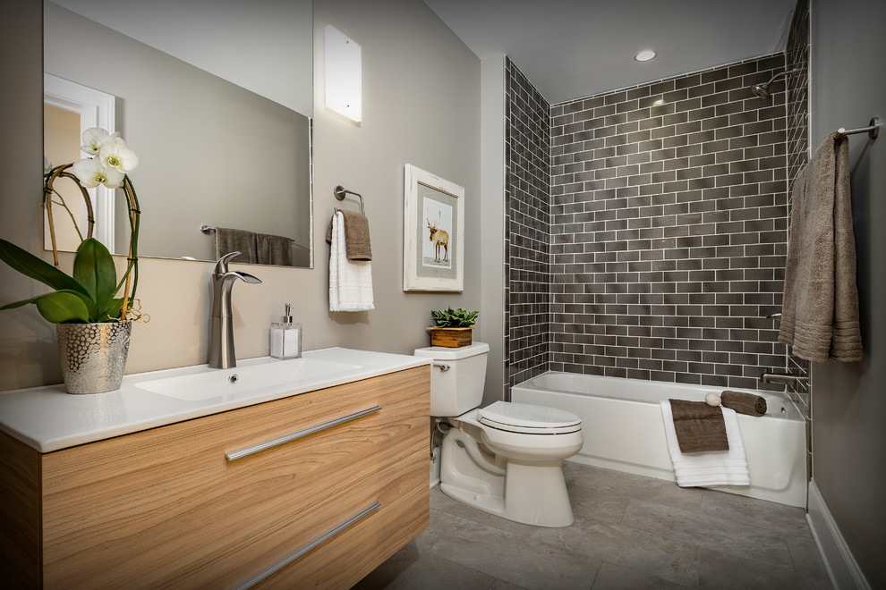 Inspiration for a mid-sized contemporary 3/4 subway tile light wood floor and beige floor bathroom remodel in Atlanta with flat-panel cabinets, light wood cabinets, a two-piece toilet, gray walls, an integrated sink and solid surface countertops