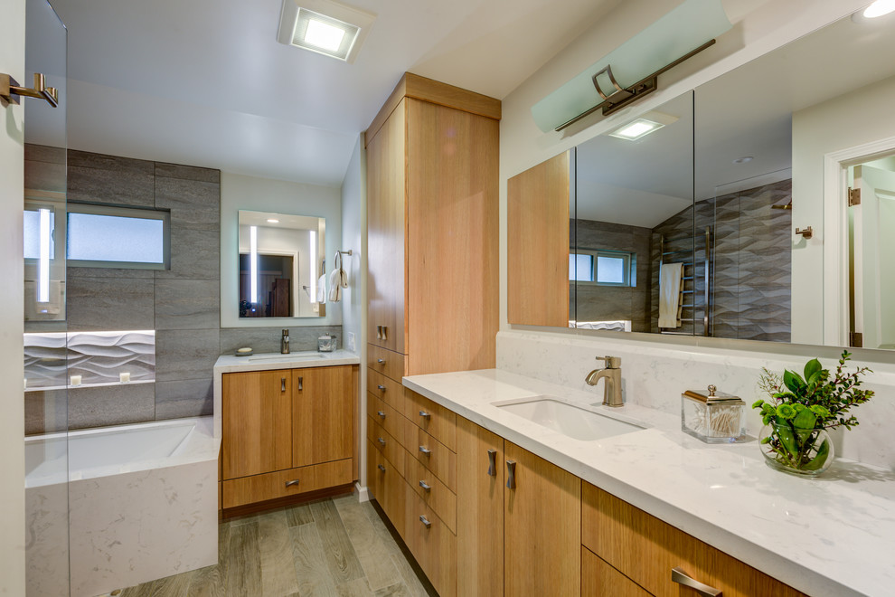 Large trendy master gray tile and ceramic tile multicolored floor and porcelain tile bathroom photo in San Francisco with flat-panel cabinets, white walls, quartz countertops, an undermount tub, a two-piece toilet, light wood cabinets and an undermount sink