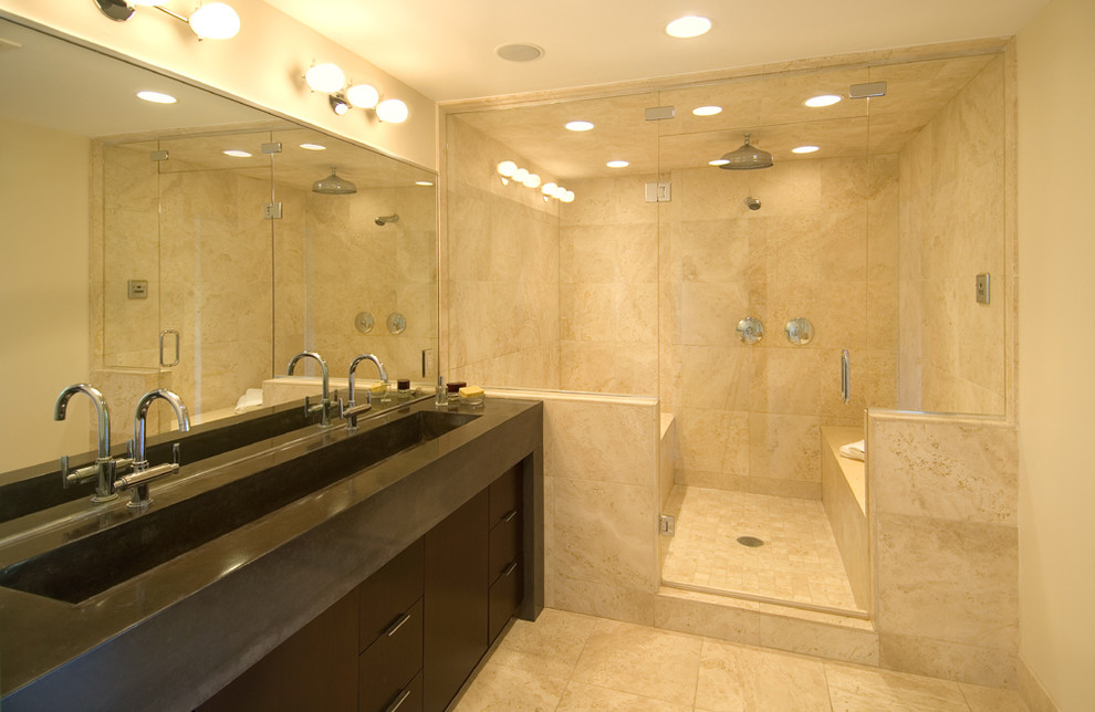 Пример оригинального дизайна: большая главная ванная комната в современном стиле с монолитной раковиной, плоскими фасадами, темными деревянными фасадами, столешницей из бетона, полновстраиваемой ванной, душем над ванной, раздельным унитазом, бежевой плиткой, каменной плиткой, белыми стенами и полом из травертина