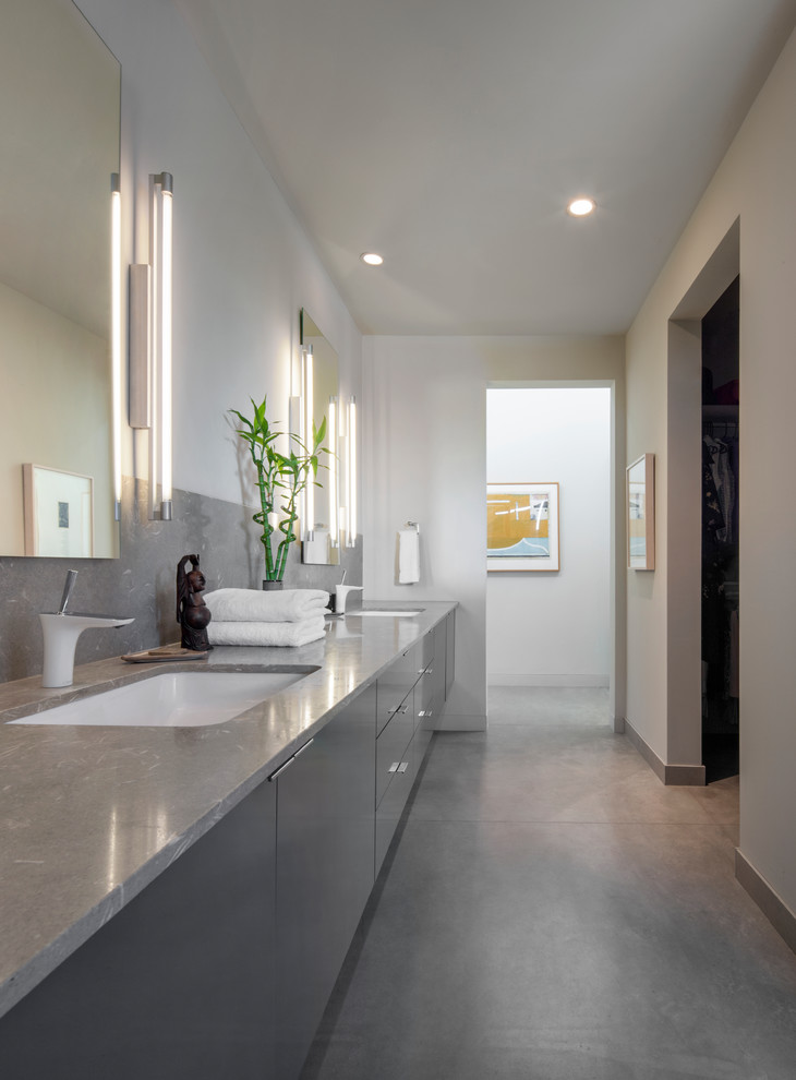 Exemple d'une salle de bain tendance avec un placard à porte plane, des portes de placard grises, un mur beige, un lavabo encastré et un sol gris.