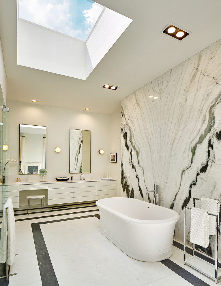 Exemple d'une très grande salle de bain principale tendance avec un placard à porte plane, des portes de placard blanches, une baignoire indépendante, des dalles de pierre et un mur multicolore.