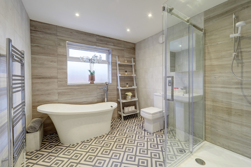 Foto på ett mellanstort funkis badrum, med ett fristående badkar, en hörndusch, klinkergolv i keramik, ett piedestal handfat, flerfärgat golv, brun kakel, grå kakel, grå väggar och dusch med skjutdörr