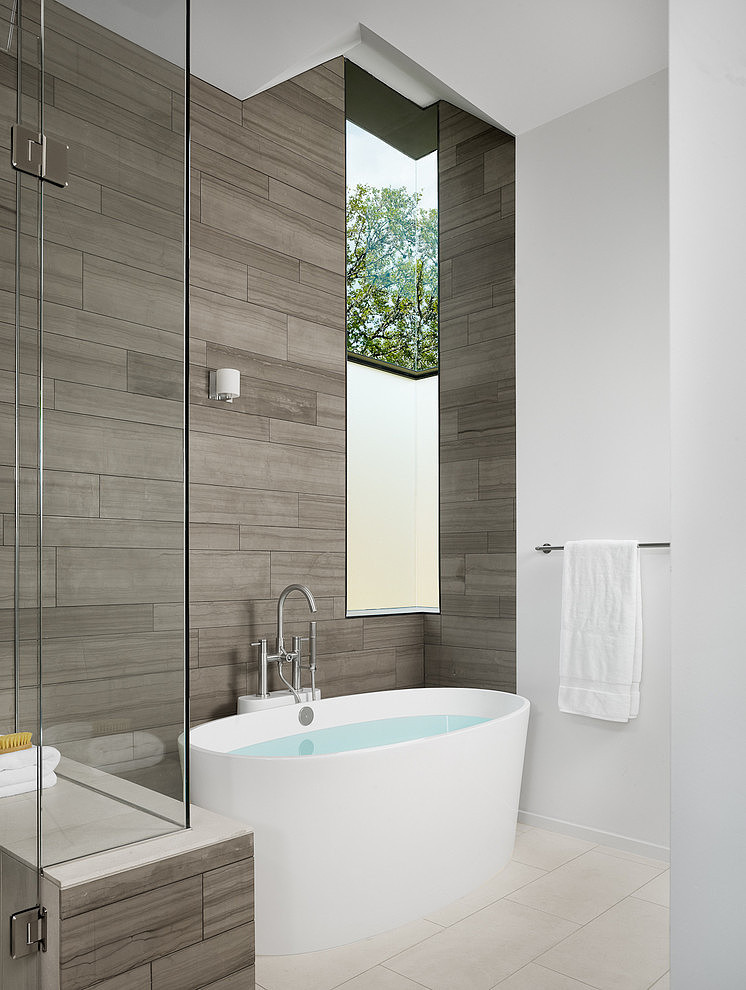 Bild på ett funkis badrum, med ett fristående badkar, grå kakel och vita väggar