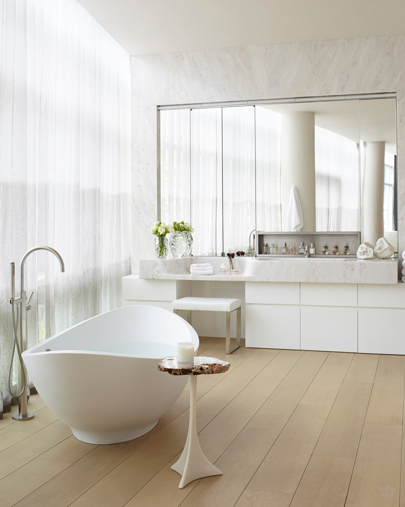 Modernes Badezimmer mit flächenbündigen Schrankfronten, weißen Schränken, freistehender Badewanne und braunem Holzboden in New York