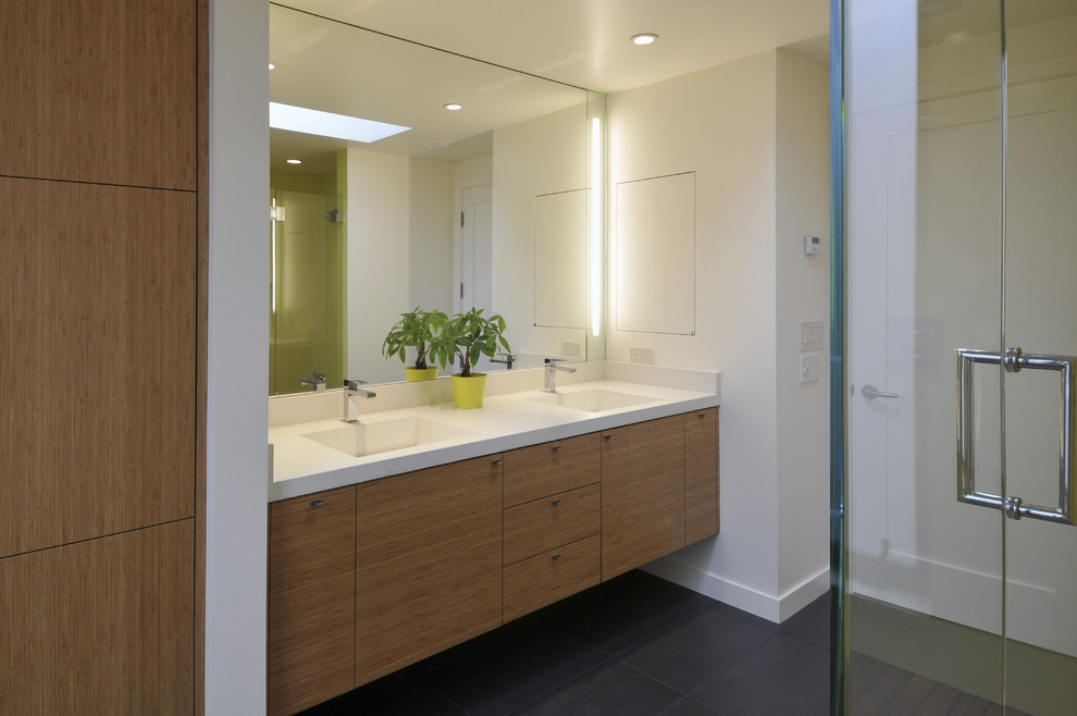 Стильный дизайн: ванная комната в современном стиле с монолитной раковиной, плоскими фасадами, фасадами цвета дерева среднего тона, серой плиткой и белыми стенами - последний тренд