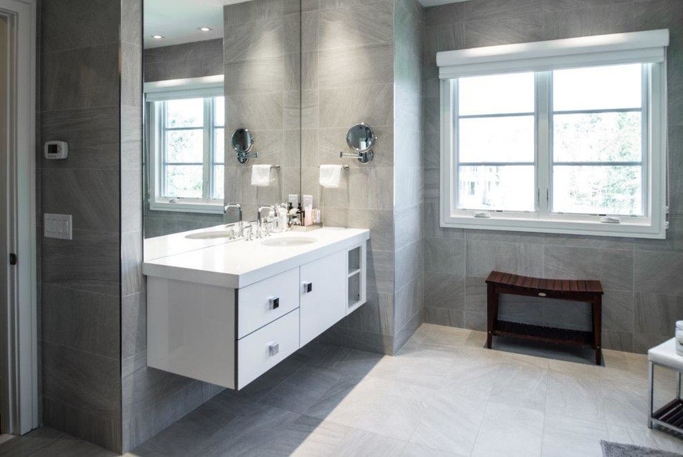 Immagine di una stanza da bagno minimal con ante lisce, ante bianche, lavabo sottopiano e piastrelle grigie