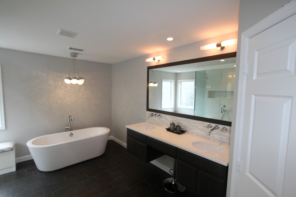 Photo of a medium sized contemporary ensuite bathroom in DC Metro with a submerged sink, flat-panel cabinets, dark wood cabinets, engineered stone worktops, a freestanding bath, a corner shower, a two-piece toilet, white tiles, porcelain tiles, grey walls and porcelain flooring.