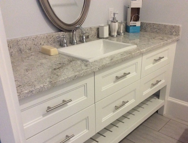 Immagine di una stanza da bagno design con ante con riquadro incassato, ante bianche, lavabo da incasso e top in granito