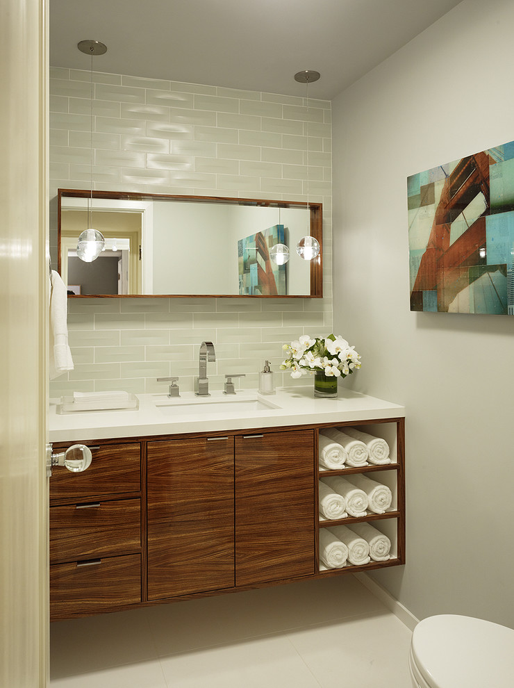 Cette image montre une salle de bain design en bois brun avec un lavabo encastré, un carrelage gris, un carrelage métro et un placard à porte plane.