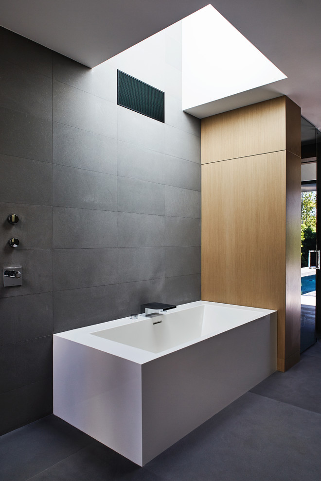 Modern inredning av ett stort en-suite badrum, med släta luckor, skåp i ljust trä, ett hörnbadkar, en öppen dusch, grå kakel, stenkakel, bänkskiva i betong, med dusch som är öppen, grå väggar och grått golv