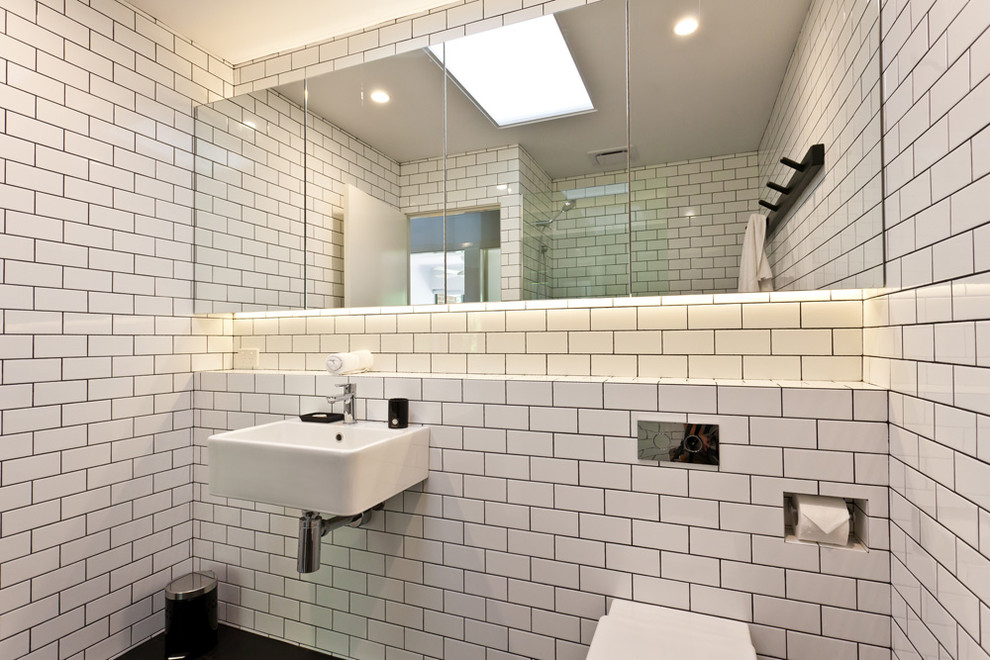 Modern inredning av ett badrum, med tunnelbanekakel, ett väggmonterat handfat och en vägghängd toalettstol