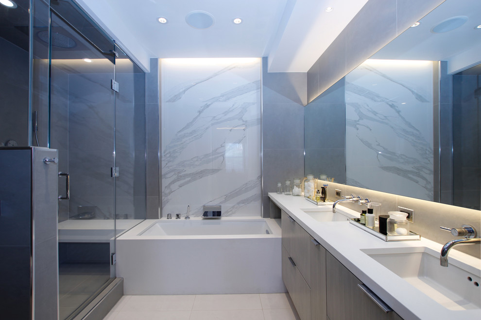 Inspiration pour une salle de bain principale design avec un placard à porte plane, une baignoire encastrée, un lavabo encastré, une douche d'angle, un mur gris et une cabine de douche à porte battante.