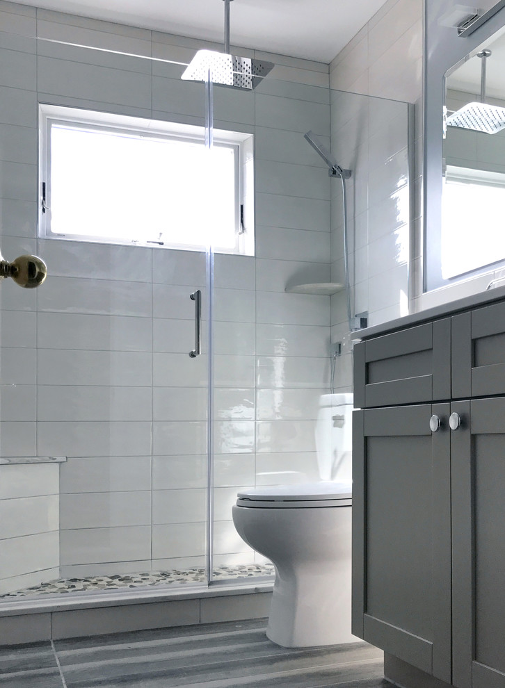 На фото: ванная комната среднего размера в современном стиле с фасадами в стиле шейкер, серыми фасадами, душем в нише, раздельным унитазом, белой плиткой, керамической плиткой, белыми стенами, полом из керамической плитки, врезной раковиной, столешницей из искусственного кварца, серым полом и душем с распашными дверями