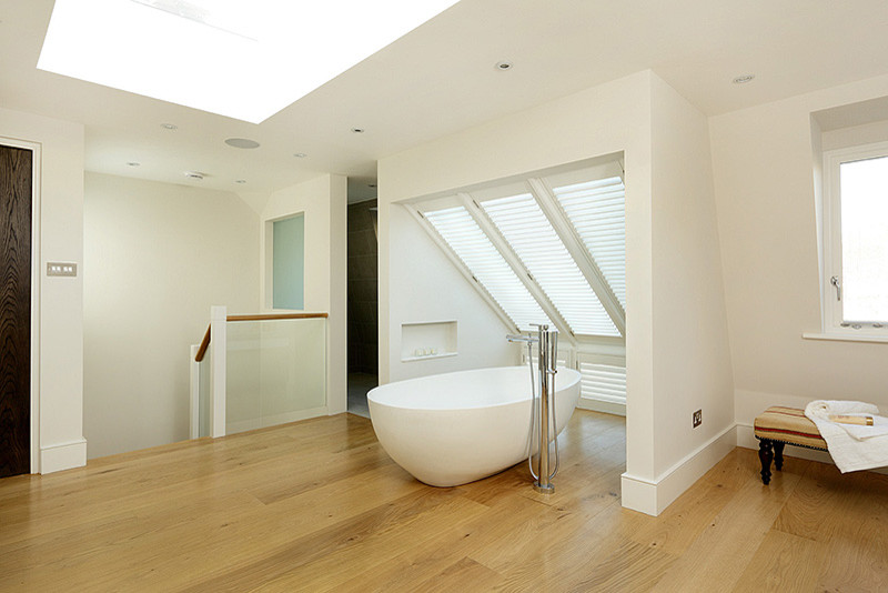 This is an example of a contemporary family bathroom in London with a vessel sink, flat-panel cabinets, a freestanding bath, an alcove shower and white walls.